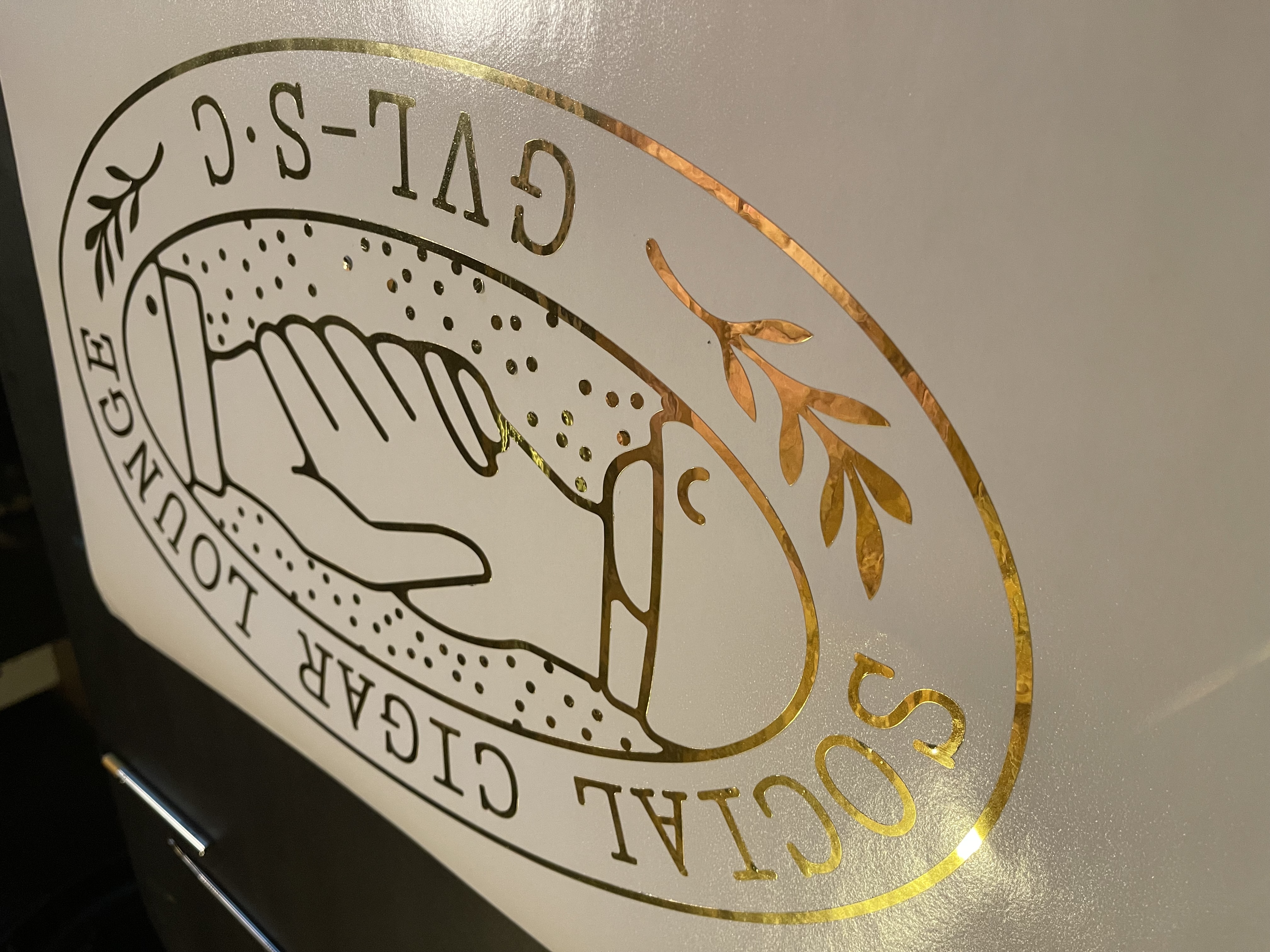 GVL Social Cigar Lounge gold foil window decal with hand and cigar illustration